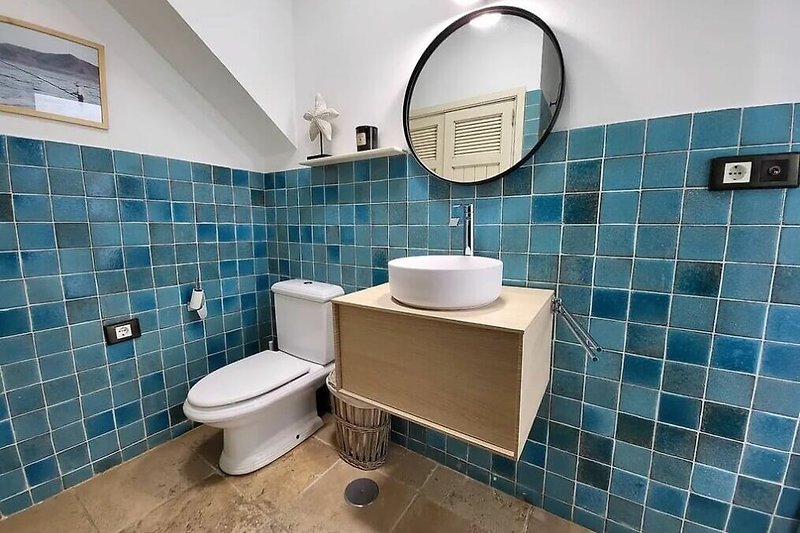 Baño moderno con espejo y grifo azul.
