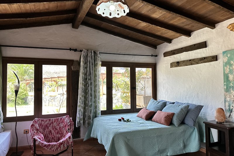 Schlafzimmer mit gemütlichem Bett, Fenster und Pflanze.