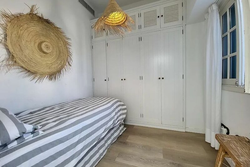 Hermoso dormitorio con suelo de madera y una elegante lámpara colgante.