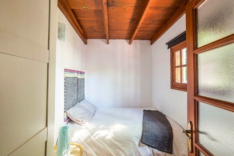 Cómoda habitación con cama de madera y ventana amplia.