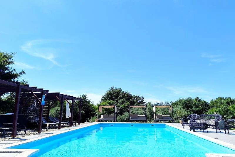 Entspannen Sie am Pool mit Palmen und bequemen Sonnenliegen.