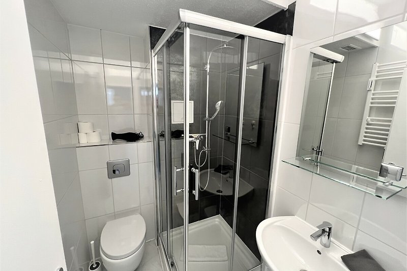 Schwarzes Badezimmer mit Spiegel, Waschbecken und Duschtür.