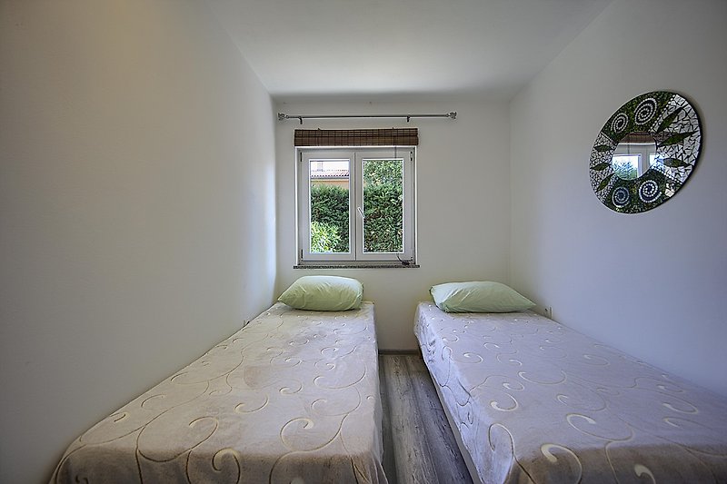 Schlafzimmer mit bequemem Bett, Fenster und Holzmöbeln.