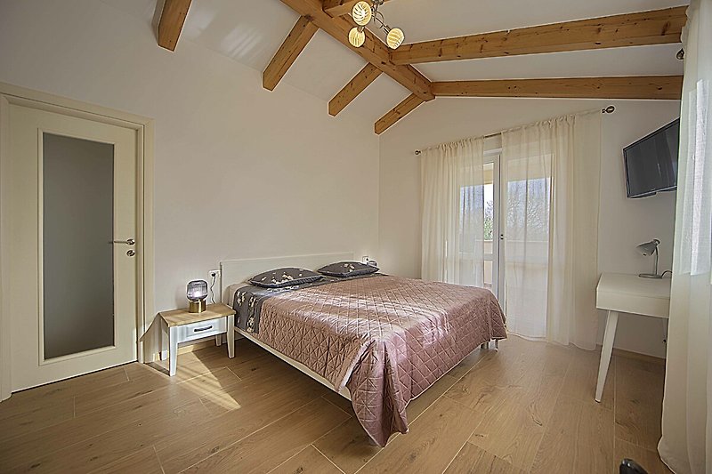 Gemütliches Schlafzimmer mit Holzbett, Fenster und Bettwäsche.