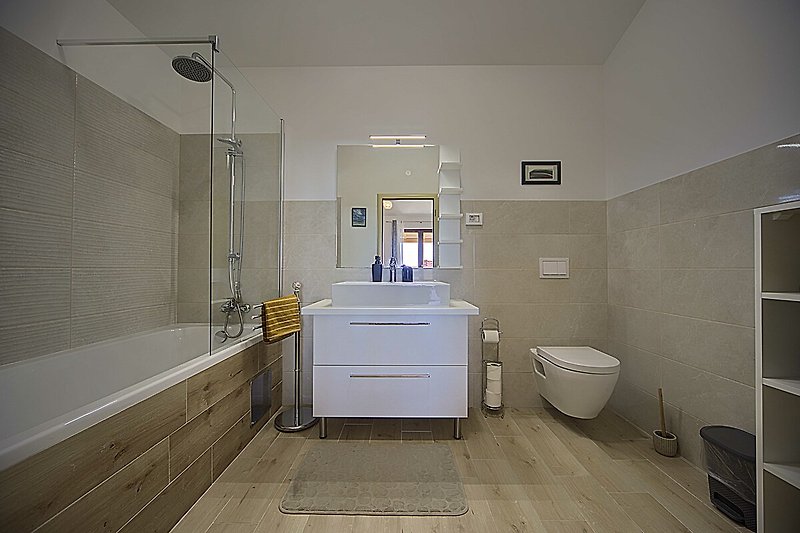 Prekrasna kupaonica s drvenim podom, ogledalom i metalnim slavinama.
