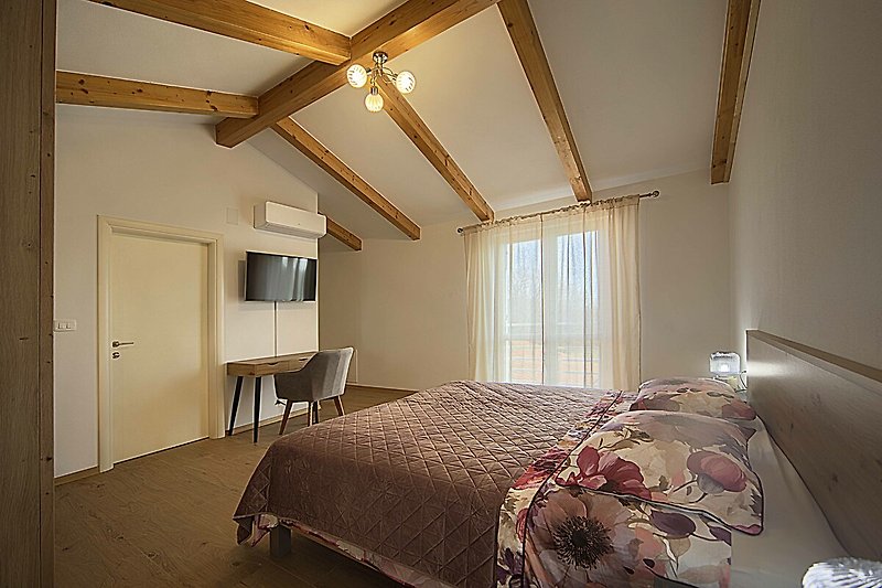 Schlafzimmer mit Holzbett, Fenster und Decke.