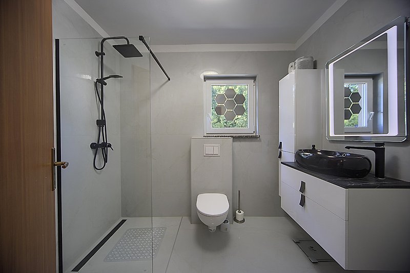 Modernes Badezimmer mit Dusche, Fenster und Pflanze.