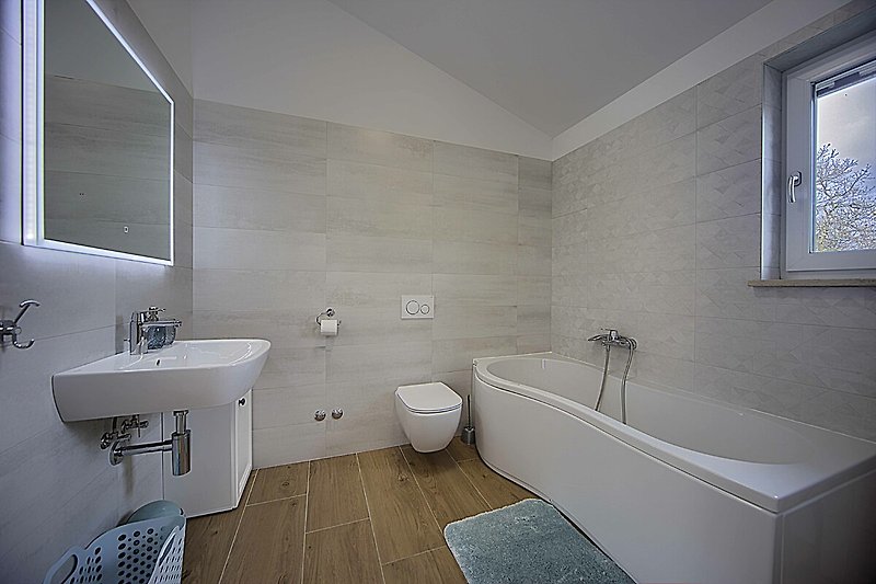 Modernes Badezimmer mit Badewanne, Spiegel und Fensterblick.