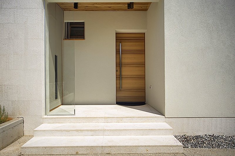 Otkrijte očaravajuću fasadu s drvenim vratima i stepenicama. Uživajte u šarmu ovog doma.