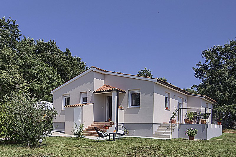 Charmantes Haus mit Veranda, Garten und blühenden Pflanzen.