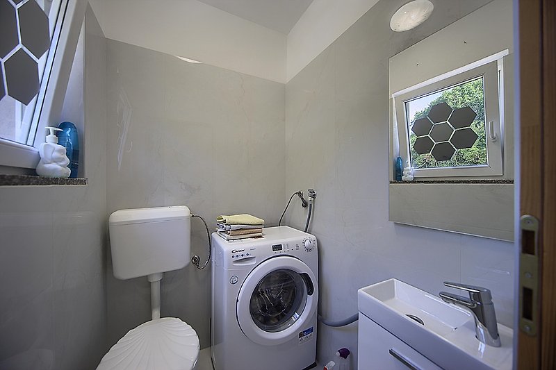 Moderne Waschküche mit Waschmaschine, Trockner und viel Licht.