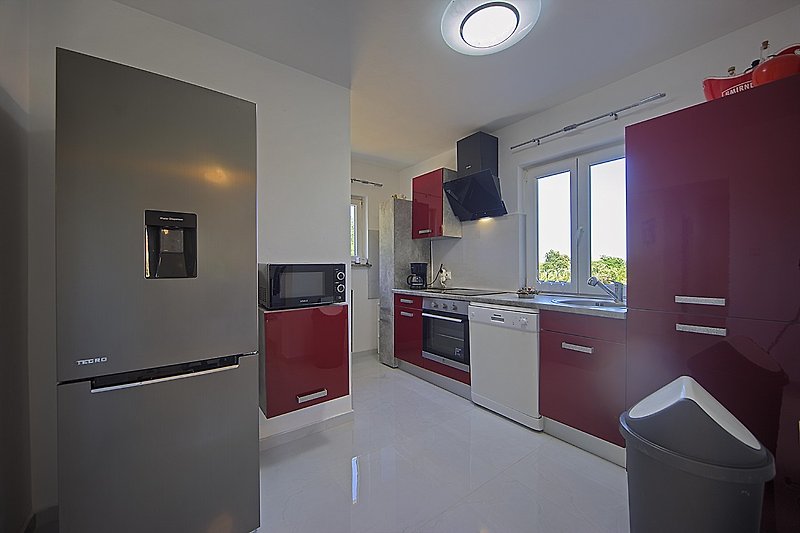 Moderne Küche mit Schränken, Arbeitsplatte, Geräten und Fenster.