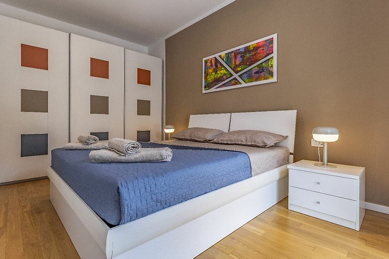 Udobna spavaća soba s lijepim drvenim namještajem i udobnim krevetom.