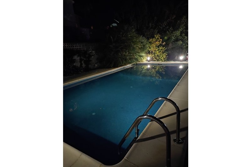 Schwimmen imvon außen beleuchteten Pool bei Nacht