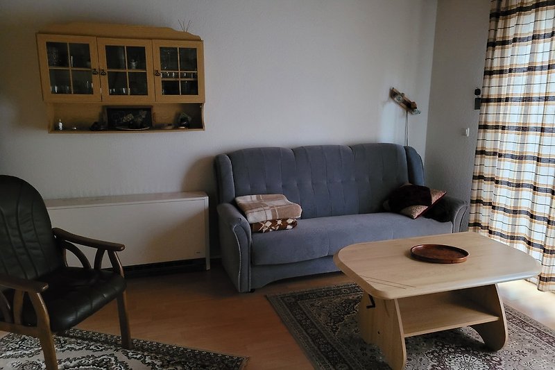 Wohnzimmer mit bequemer Couch, Tisch, Fenster und Holzboden.