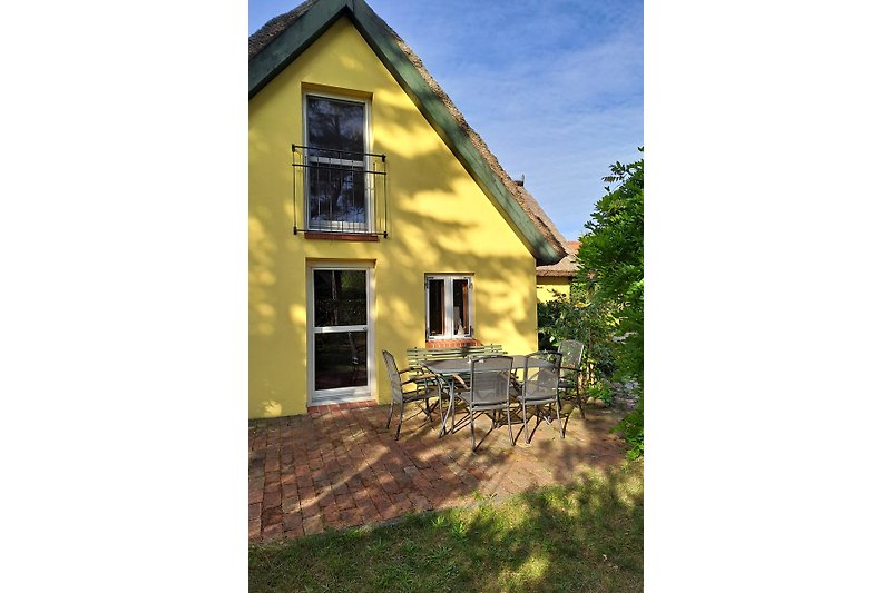 Schönes Haus mit gelber Fassade, umgeben von Bäumen und Pflanzen.