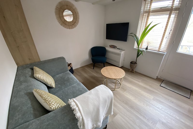 Gemütliches Wohnzimmer mit PVC Bodem, Fenstern und Pflanzen. Entspannen Sie sich auf dem bequemen Sofa.