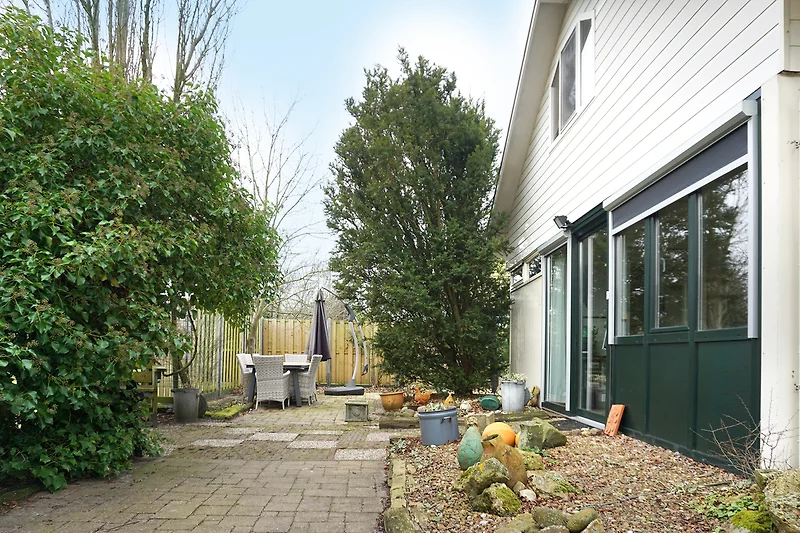 Gepflegter Garten mit Sträuchern, Einfahrt und schattigem Hof.