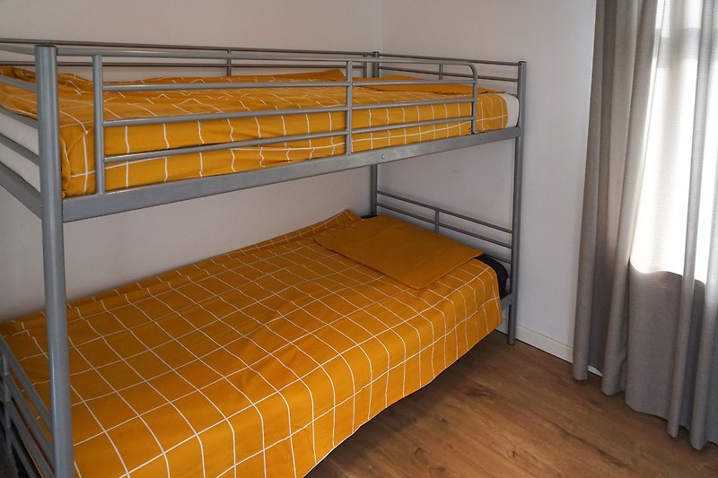 Gemütliches Schlafzimmer mit Holzbett und Metallgeländer.