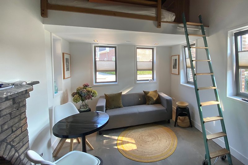 Wohnzimmer mit Holzdecke, Treppe und Tageslicht.