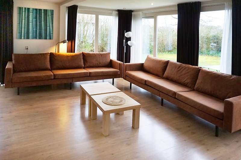 Wohnzimmer mit brauner Couch, Tisch, Pflanze und Holzmöbeln.