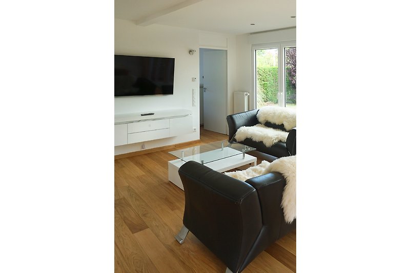 Gemütliches Wohnzimmer mit Holzmöbeln, Fenster und Fernseher.