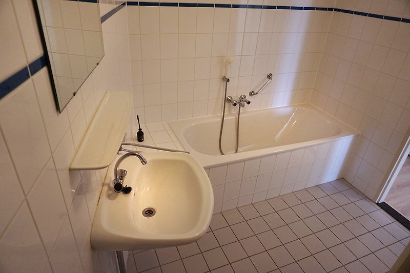 Ein stilvolles Badezimmer mit Holzboden, Marmorwaschbecken und Keramikfliesen.