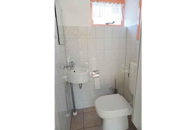 Badezimmer mit lila Akzenten, Keramikwaschbecken und Toilette.