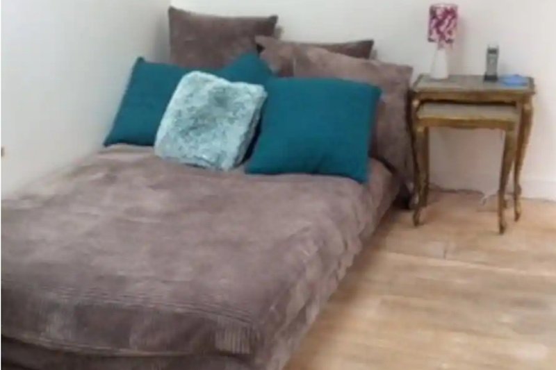 Wohnzimmer mit bequemer Couch, Kissen und Holzmöbeln.