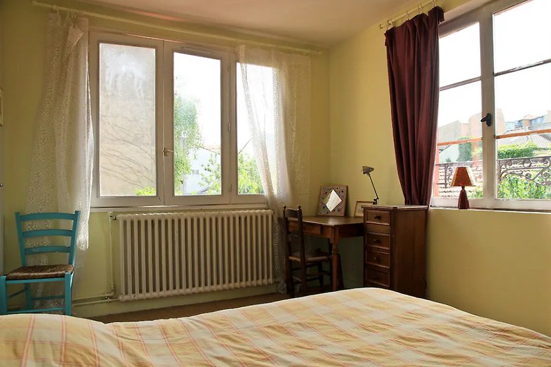 Schlafzimmer mit gemütlichem Bett, Vorhängen und Pflanze.
