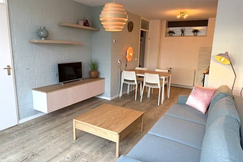 Wohnzimmer mit Holzdekor, Tisch, Beleuchtung und Pflanzen.