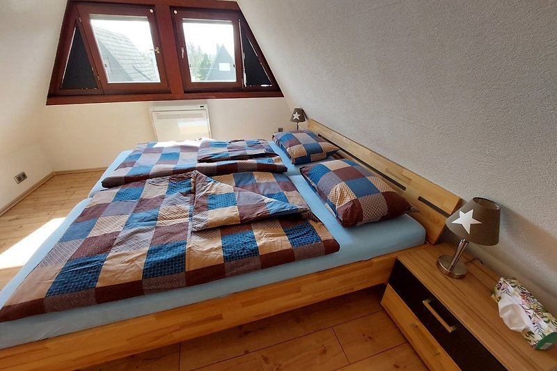Gemütliches Schlafzimmer mit Holzmöbeln und großem Fenster.
