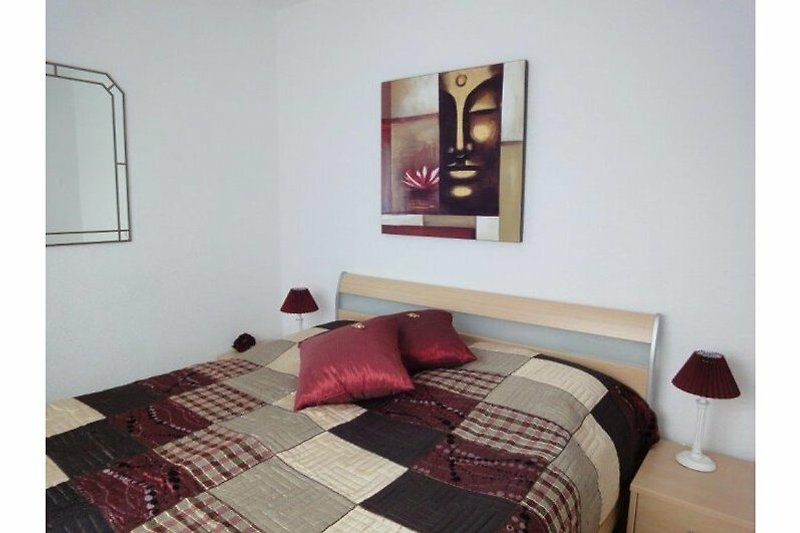 Stilvolles Schlafzimmer mit gemütlichem Bett und magentafarbenen Akzenten.