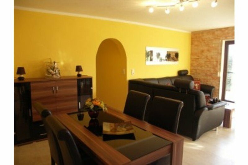 Wohnzimmer mit Holzmöbeln, Tisch, Couch und Stuhl.