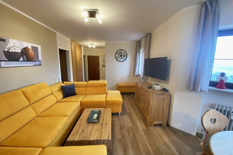 Gemütliches Wohnzimmer mit bequemer Couch, Tisch und Fernseher.