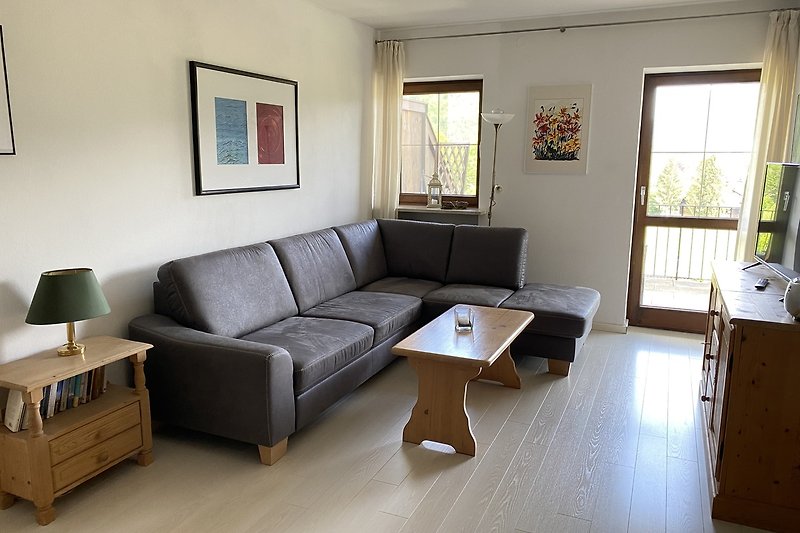 Modernes Wohnzimmer mit Schlafsofa, Couchtisch und großen Fenstern.