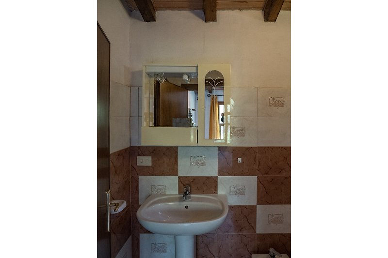 Schönes Badezimmer mit Spiegel, braunem Holz und Waschbecken.