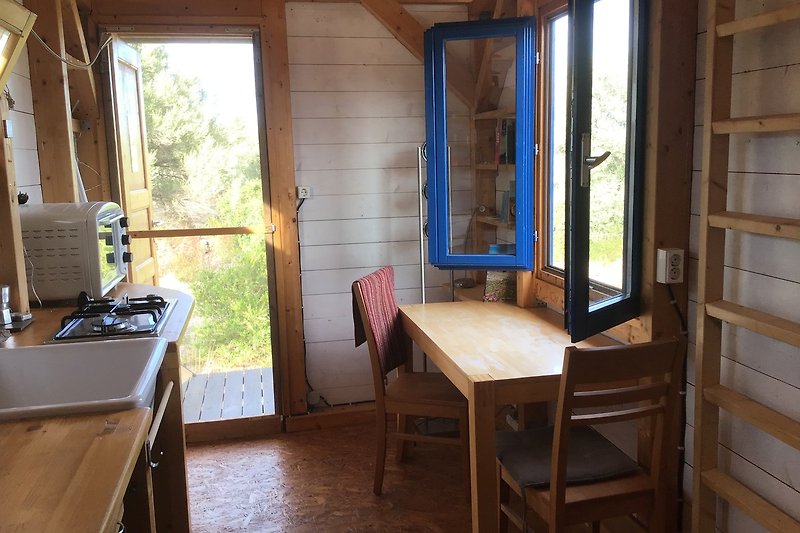 Gemütliche Ferienwohnung mit Holzboden, Fenster und Tisch.