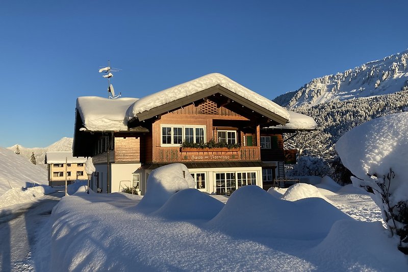 Winterliches Haus Narzisse mit Straußberghof im Hintergrund