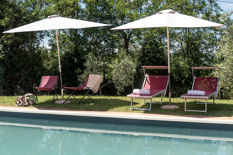 Entspannen Sie im Schatten am Pool mit Blick auf die grüne Landschaft und genießen Sie die Sonne.