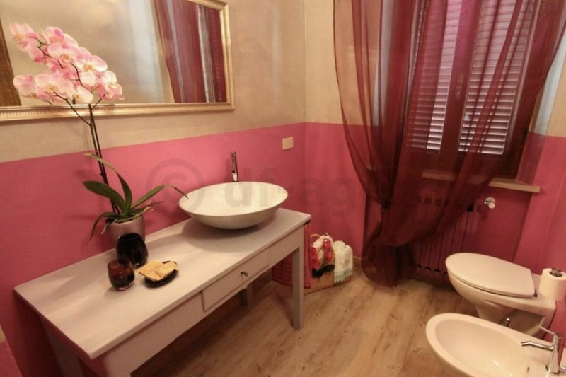 Elegantes Badezimmer mit lila Vorhang und Blumen.