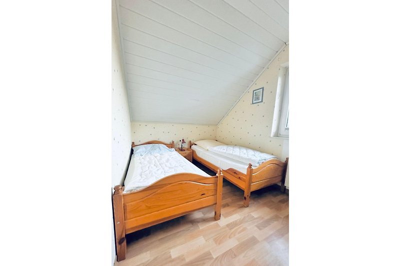 Schönes Schlafzimmer mit Holzbett, Fenster und gemütlicher Einrichtung.