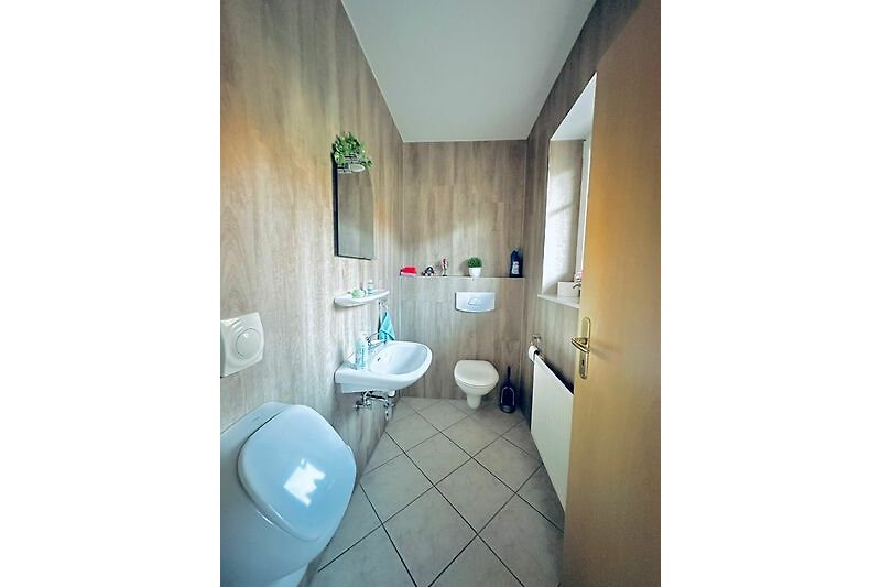 Gemütliches Badezimmer mit lila Akzenten, Holzboden und Fliesen.
