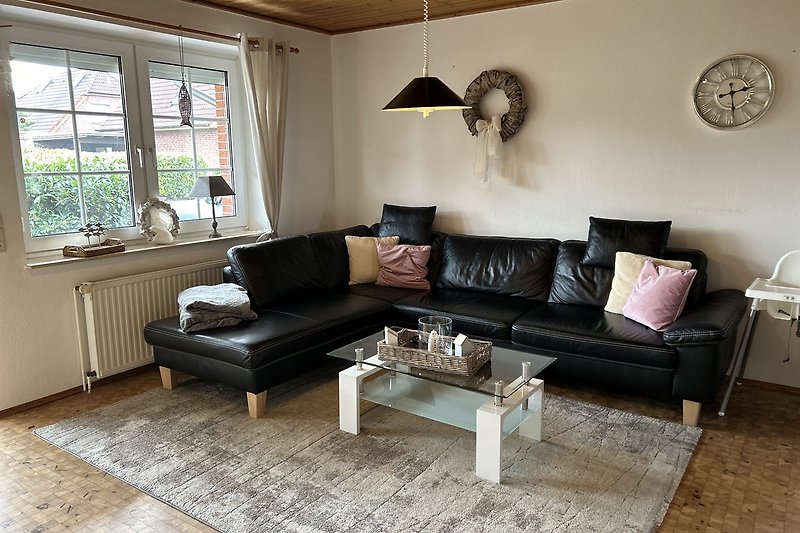 Wohnzimmer mit Holzmöbeln, Couch, Tisch, Uhr und Pflanze.