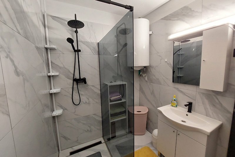 Moderan interijer kupaonice s umivaonikom, slavinom i tušem. Apartman br. 2