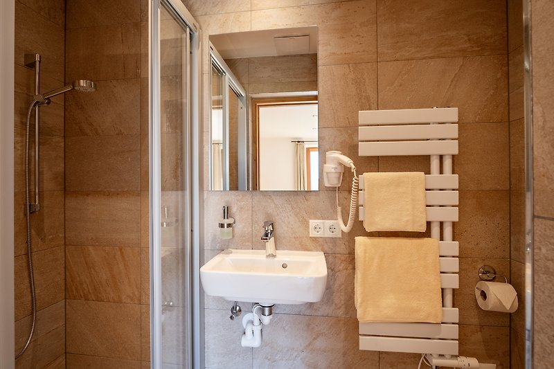 Schönes Badezimmer mit braunem Holz, Spiegel und Waschbecken.