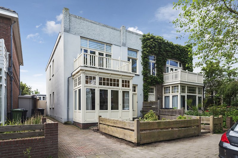 Charmantes Haus mit Garten, Bäumen und geparktem Auto in ruhiger Gegend.