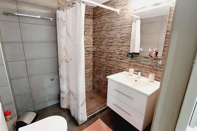 Przestronna łazienka z pięknym lustrem i eleganckim umywalkiem.