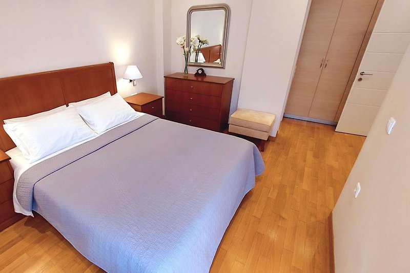 Komfortowa sypialnia z drewnianym łóżkiem i designerską lampą.
