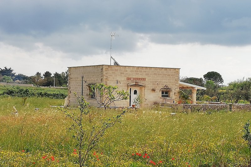 Natursteinhaus il cocco, umgeben von grünen Feldern.